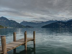 closeup photo of brown wooden dock facing mountain and calm body of water